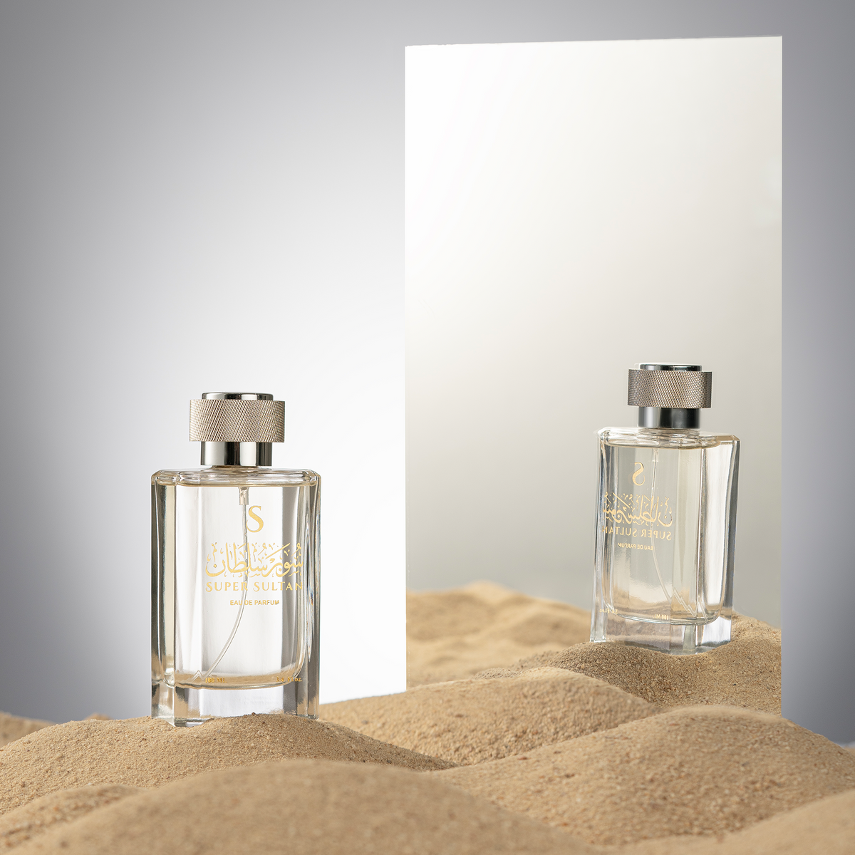 عطر سوبر سلطان 100 مل على رمال أمام مرآة تعكس الزجاجة