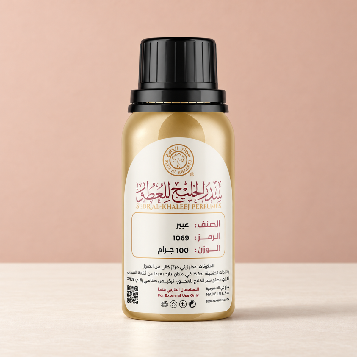 Sedr Al-Khaleej Abeer perfume oil, gold bottle on ivory ceramic against a dusty peach backdrop in soft daylight
