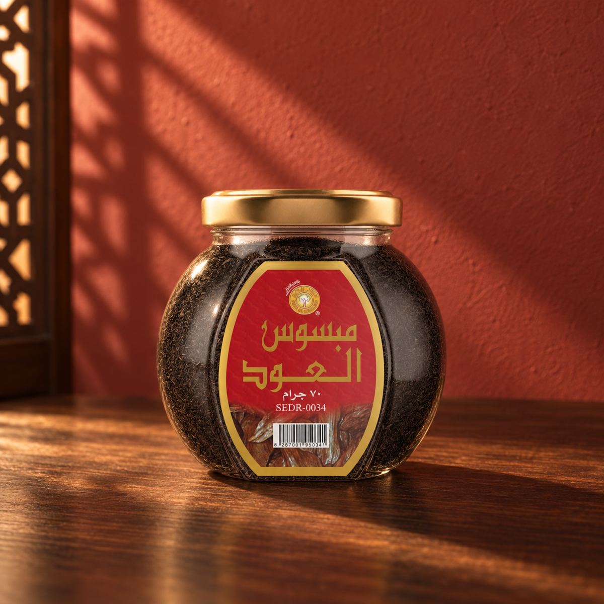 Al Oud Mabsos 70 g from Sedr Al-Khaleej; closed glass jar with a gold lid on walnut wood against a brick red plaster wall, with angled sunlight and a wooden screen shadow on the left.