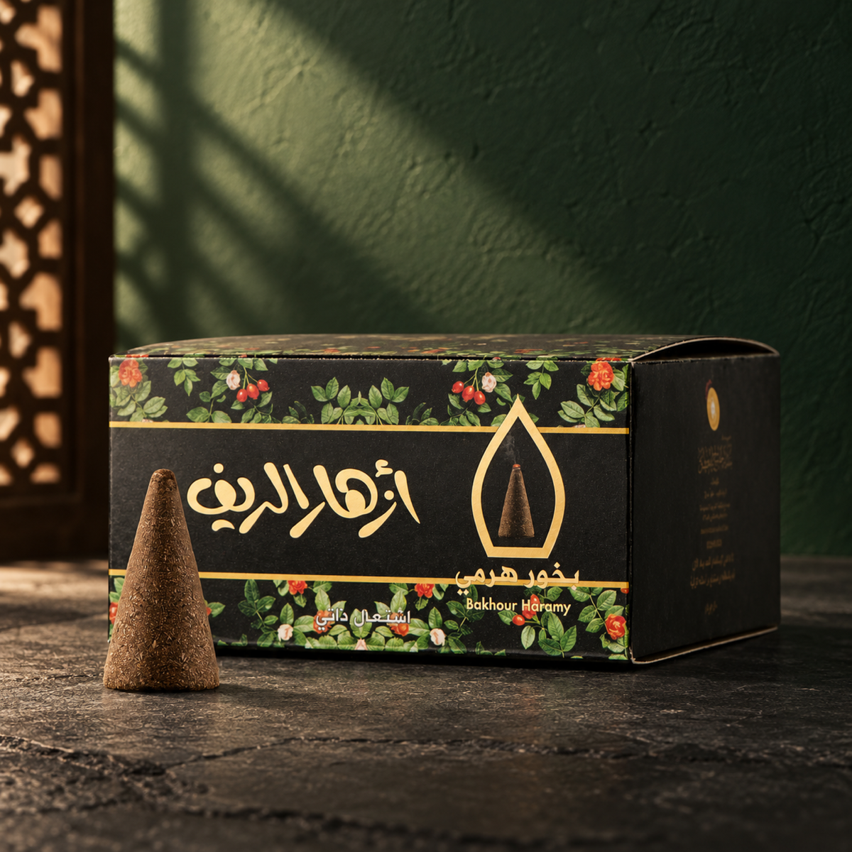 Azhar Al-Reef Pyramid Bakhoor 50 g from Sedr Al-Khaleej; black incense box with floral printing and one cone on dark slate against a deep green wall.
