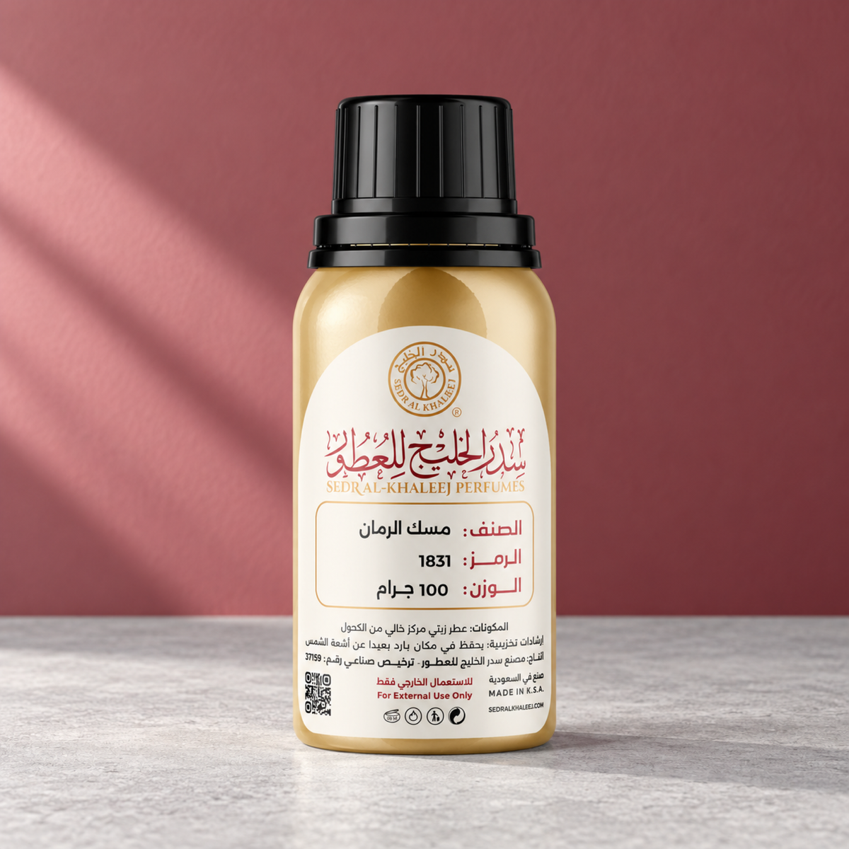 زيت عطري مسك الرمان من سدر الخليج؛ سطح معدني رمادي وخلفية توتية بضوء صباح مائل، العبوة الأصلية مغلقة.
