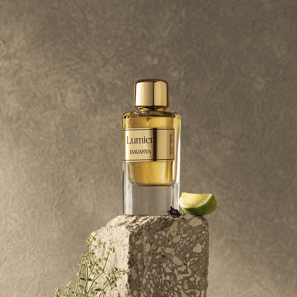 Davania Perfume 75 ml on a stone block with a lime slice and grass sprigs against a beige background