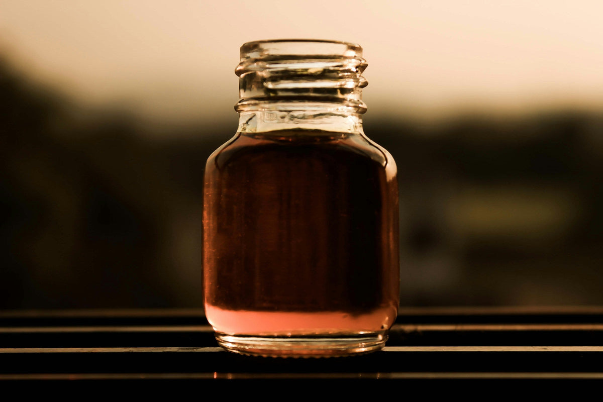 A small glass bottle of amber-coloured perfume oil in warm light