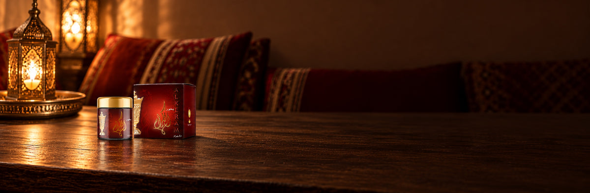 Al-Keram incense and its box on a wooden table in a majlis, beside a lit lantern