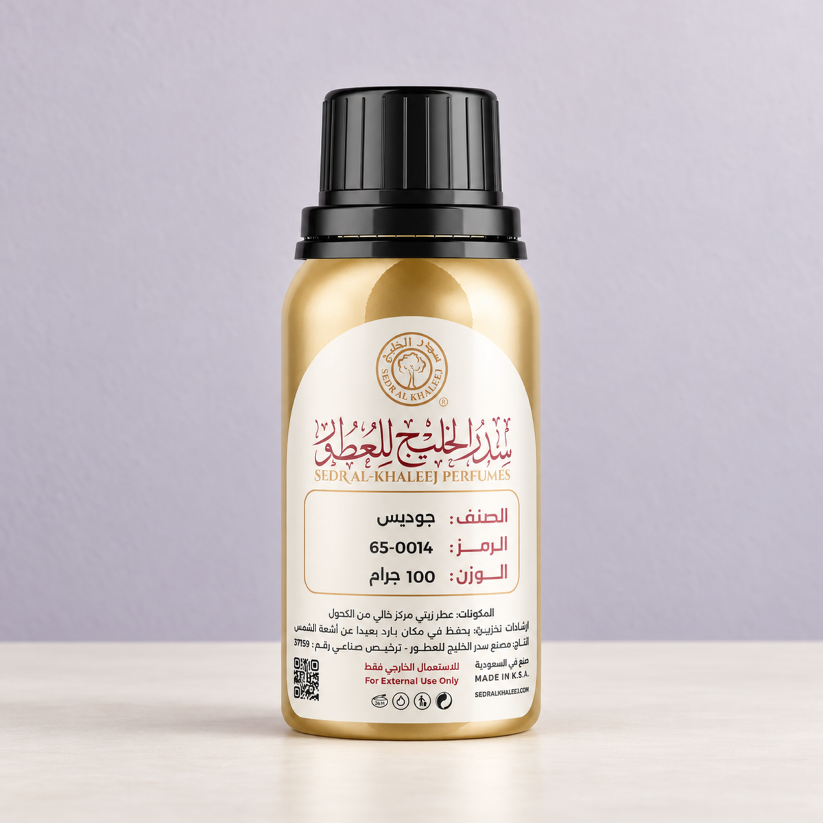 عطر زيتي مستوحى من عطر جوديس من سدر الخليج، عبوة ذهبية مغلقة على بورسلان عاجي أمام خلفية رمادي ليلكي فاتح