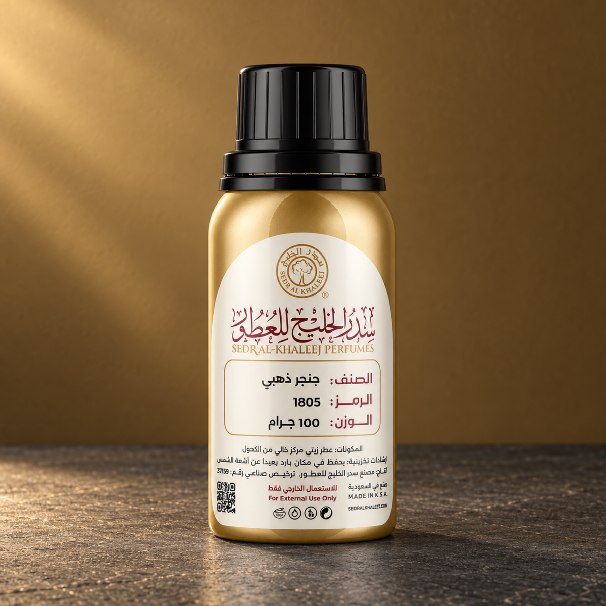 زيت عطري جنجر ذهبي من سدر الخليج، عبوة ذهبية مغلقة على بازلت فحمي أمام خلفية برونزي مغرّي هادئ