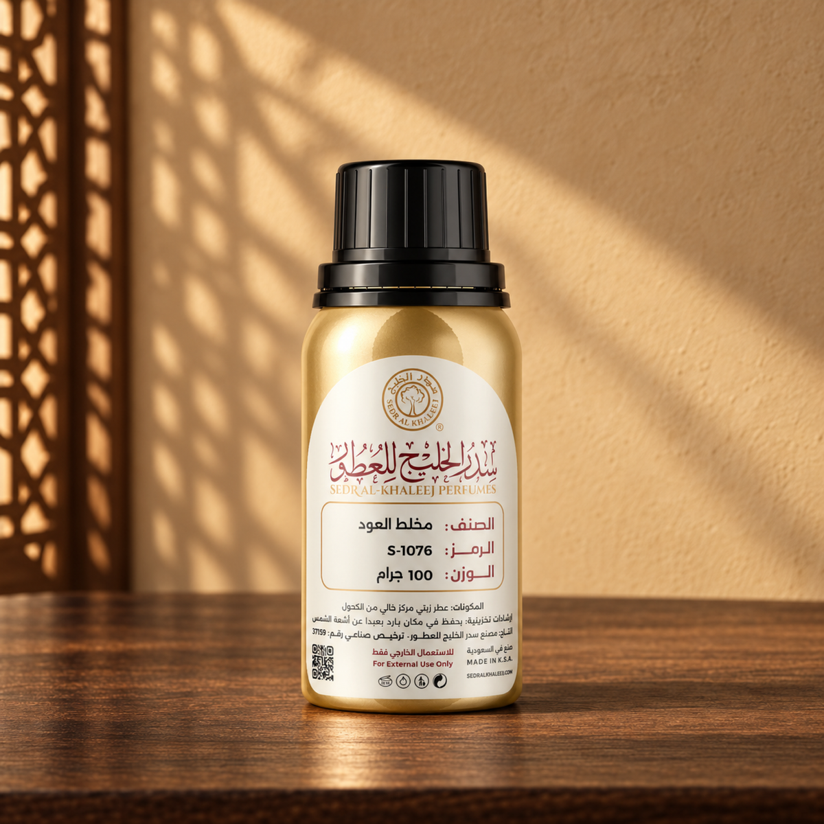 Sedr Al-Khaleej Mukhalat Al Oud perfume oil in a gold bottle with a black cap and cream label, on walnut wood against a sand plaster wall with sunlight and a mashrabiya shadow.