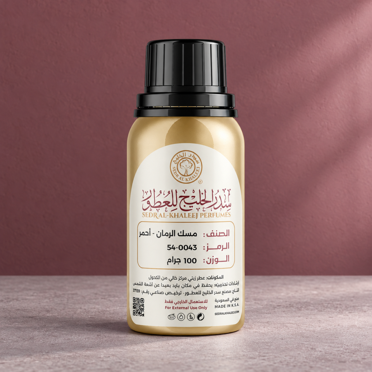 زيت عطري مسك الرمان أحمر من سدر الخليج؛ خرسانة وردية رمادية وخلفية حمراء توتية بضوء نافذة عمودي، العبوة الأصلية مغلقة.