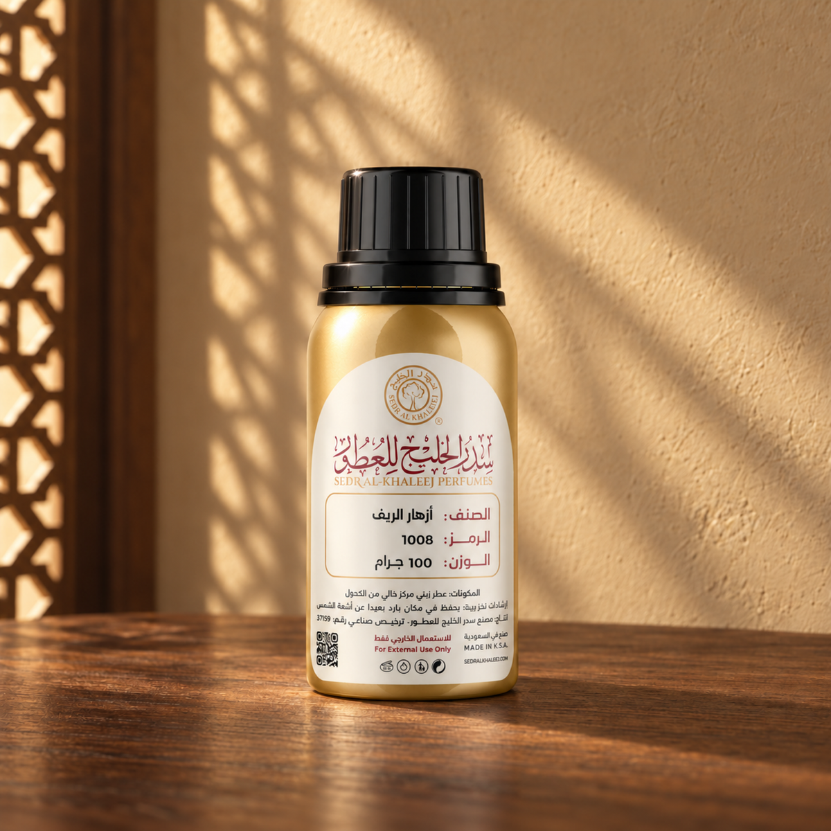 Sedr Al-Khaleej Azhar Al Reef perfume oil in a gold bottle with a black cap and cream label, on walnut wood against a sand plaster wall with sunlight and a mashrabiya shadow.